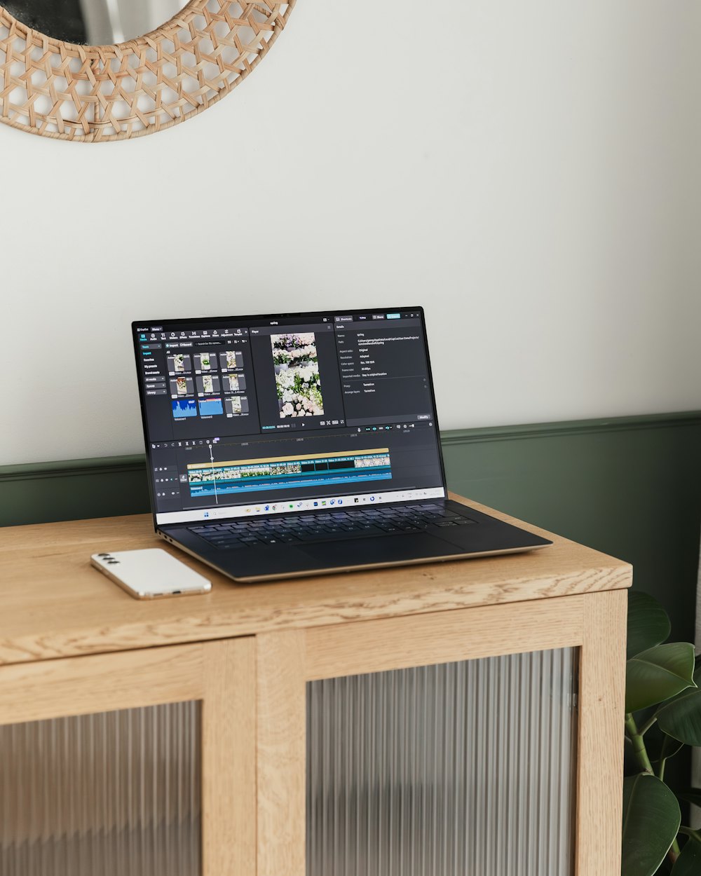 A laptop on a wooden desk showing a video editing timeline