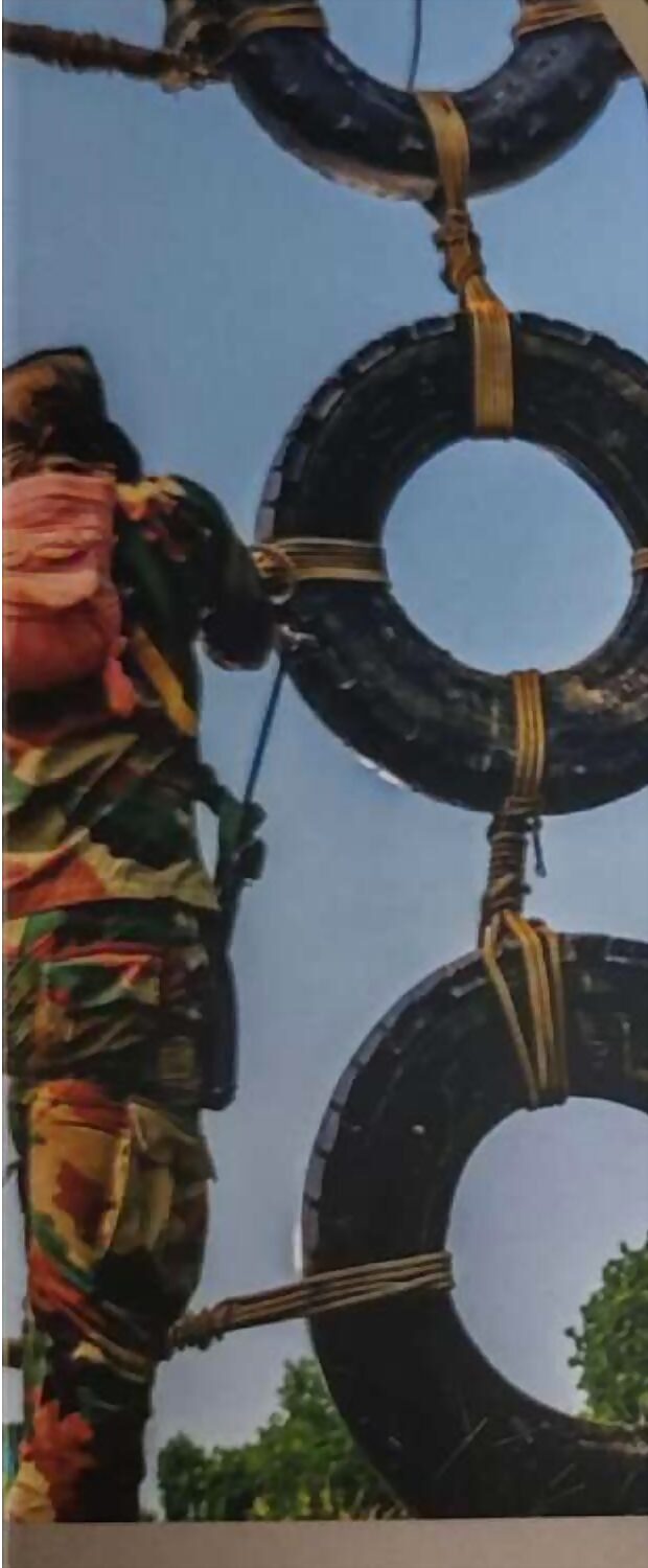 A recruit swinging through suspended tyres on an obstacle course